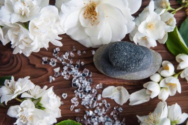 Gri Zen taşlarından piramitler, güzel taze beyaz çiçekler, ahşap arka planda yeşil yapraklar. Uyum kavramı, denge ve meditasyon, spa, masaj, rahatlama