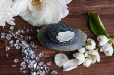 Gri Zen taşlarından piramitler, güzel taze beyaz çiçekler, ahşap arka planda yeşil yapraklar. Uyum kavramı, denge ve meditasyon, spa, masaj, rahatlama