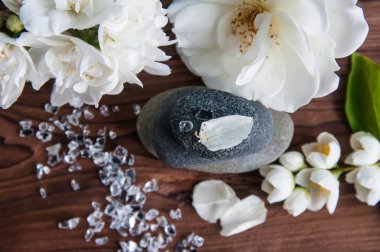 Gri Zen taşlarından piramitler, güzel taze beyaz çiçekler, ahşap arka planda yeşil yapraklar. Uyum kavramı, denge ve meditasyon, spa, masaj, rahatlama