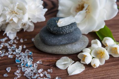 Gri Zen taşlarından piramitler, güzel taze beyaz çiçekler, ahşap arka planda yeşil yapraklar. Uyum kavramı, denge ve meditasyon, spa, masaj, rahatlama