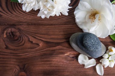 Gri Zen taşlarından piramitler, güzel taze beyaz çiçekler, ahşap arka planda yeşil yapraklar. Uyum kavramı, denge ve meditasyon, spa, masaj, rahatlama