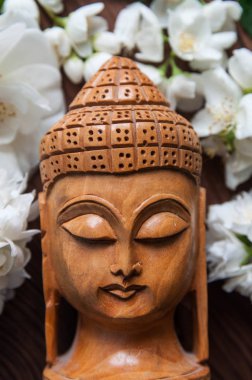 Güzel taze beyaz çiçek yeşil Buda heykeli ahşap arka plan üzerinde bırakır. Uyum, denge ve meditasyon, spa, kavramı masaj, sakin ol