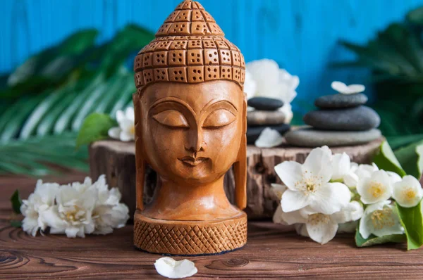 Gri Zen taşlarından piramitler, güzel taze beyaz çiçekler yeşil yapraklar ve ahşap arka planda Buda heykeli. Uyum kavramı, denge ve meditasyon, spa, masaj, rahatlama