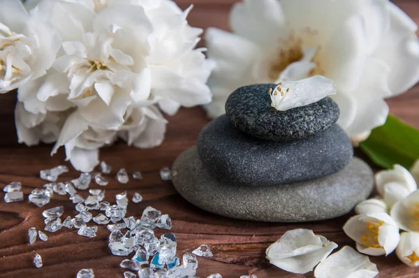 Gri Zen taşlarından piramitler, güzel taze beyaz çiçekler, ahşap arka planda yeşil yapraklar. Uyum kavramı, denge ve meditasyon, spa, masaj, rahatlama