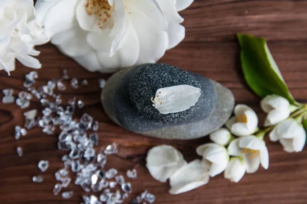 Gri Zen taşlarından piramitler, güzel taze beyaz çiçekler, ahşap arka planda yeşil yapraklar. Uyum kavramı, denge ve meditasyon, spa, masaj, rahatlama