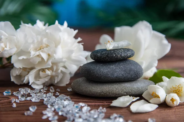 Gri Zen taşlarından piramitler, güzel taze beyaz çiçekler, ahşap arka planda yeşil yapraklar. Uyum kavramı, denge ve meditasyon, spa, masaj, rahatlama