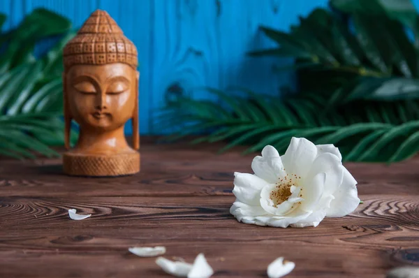 Güzel taze beyaz çiçek yeşil Buda heykeli ahşap arka plan üzerinde bırakır. Uyum, denge ve meditasyon, spa, kavramı masaj, sakin ol