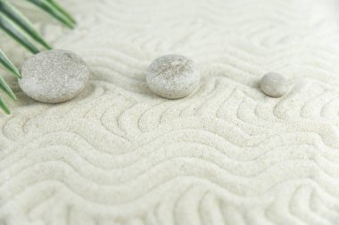 Zen bahçesi. Beyaz ve gri Zen taşlarından piramitler soyut dalga çizimleriyle beyaz kumun üzerinde. Uyum kavramı, denge ve meditasyon, spa, masaj, rahatlama.