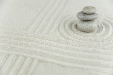 Zen bahçesi. Beyaz ve gri Zen taşlarından piramitler soyut dalga çizimleriyle beyaz kumun üzerinde. Uyum kavramı, denge ve meditasyon, spa, masaj, rahatlama.