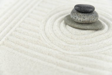 Zen bahçesi. Beyaz ve gri Zen taşlarından piramitler soyut dalga çizimleriyle beyaz kumun üzerinde. Uyum kavramı, denge ve meditasyon, spa, masaj, rahatlama.