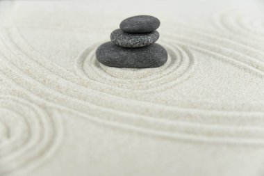 Zen bahçesi. Beyaz ve gri Zen taşlarından piramitler soyut dalga çizimleriyle beyaz kumun üzerinde. Uyum kavramı, denge ve meditasyon, spa, masaj, rahatlama.