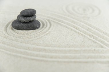 Zen bahçesi. Beyaz ve gri Zen taşlarından piramitler soyut dalga çizimleriyle beyaz kumun üzerinde. Uyum kavramı, denge ve meditasyon, spa, masaj, rahatlama.