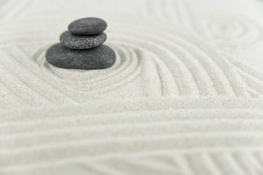 Zen bahçesi. Beyaz ve gri Zen taşlarından piramitler soyut dalga çizimleriyle beyaz kumun üzerinde. Uyum kavramı, denge ve meditasyon, spa, masaj, rahatlama.