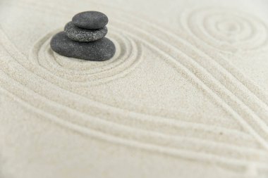 Zen bahçesi. Beyaz ve gri Zen taşlarından piramitler soyut dalga çizimleriyle beyaz kumun üzerinde. Uyum kavramı, denge ve meditasyon, spa, masaj, rahatlama.