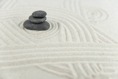 Zen bahçesi. Beyaz ve gri Zen taşlarından piramitler soyut dalga çizimleriyle beyaz kumun üzerinde. Uyum kavramı, denge ve meditasyon, spa, masaj, rahatlama.