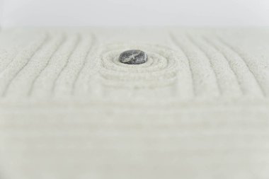 Zen bahçesi. Beyaz ve gri Zen taşlarından piramitler soyut dalga çizimleriyle beyaz kumun üzerinde. Uyum kavramı, denge ve meditasyon, spa, masaj, rahatlama.