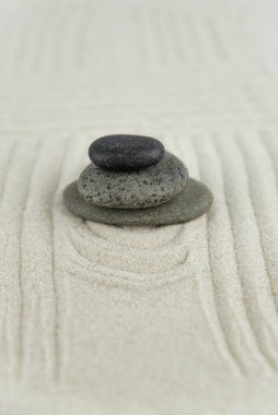 Zen bahçesi. Beyaz ve gri Zen taşlarından piramitler soyut dalga çizimleriyle beyaz kumun üzerinde. Uyum kavramı, denge ve meditasyon, spa, masaj, rahatlama.