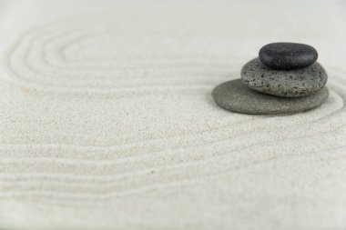 Zen bahçesi. Beyaz ve gri Zen taşlarından piramitler soyut dalga çizimleriyle beyaz kumun üzerinde. Uyum kavramı, denge ve meditasyon, spa, masaj, rahatlama.