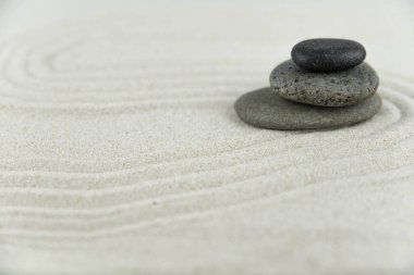 Zen bahçesi. Beyaz ve gri Zen taşlarından piramitler soyut dalga çizimleriyle beyaz kumun üzerinde. Uyum kavramı, denge ve meditasyon, spa, masaj, rahatlama.