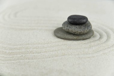 Zen bahçesi. Beyaz ve gri Zen taşlarından piramitler soyut dalga çizimleriyle beyaz kumun üzerinde. Uyum kavramı, denge ve meditasyon, spa, masaj, rahatlama.