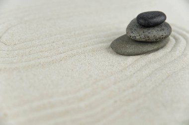Zen bahçesi. Beyaz ve gri Zen taşlarından piramitler soyut dalga çizimleriyle beyaz kumun üzerinde. Uyum kavramı, denge ve meditasyon, spa, masaj, rahatlama.