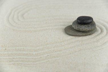 Zen bahçesi. Beyaz ve gri Zen taşlarından piramitler soyut dalga çizimleriyle beyaz kumun üzerinde. Uyum kavramı, denge ve meditasyon, spa, masaj, rahatlama.