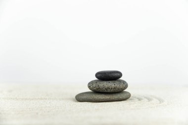 Zen bahçesi. Beyaz ve gri Zen taşlarından piramitler soyut dalga çizimleriyle beyaz kumun üzerinde. Uyum kavramı, denge ve meditasyon, spa, masaj, rahatlama.