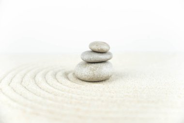 Zen bahçesi. Beyaz ve gri Zen taşlarından piramitler soyut dalga çizimleriyle beyaz kumun üzerinde. Uyum kavramı, denge ve meditasyon, spa, masaj, rahatlama.