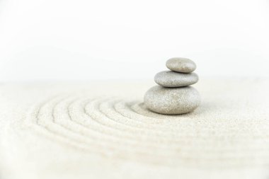 Zen bahçesi. Beyaz ve gri Zen taşlarından piramitler soyut dalga çizimleriyle beyaz kumun üzerinde. Uyum kavramı, denge ve meditasyon, spa, masaj, rahatlama.