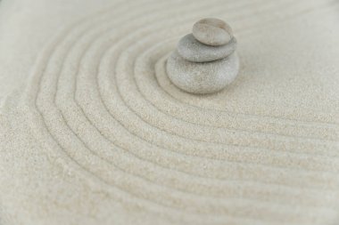 Zen bahçesi. Beyaz ve gri Zen taşlarından piramitler soyut dalga çizimleriyle beyaz kumun üzerinde. Uyum kavramı, denge ve meditasyon, spa, masaj, rahatlama.