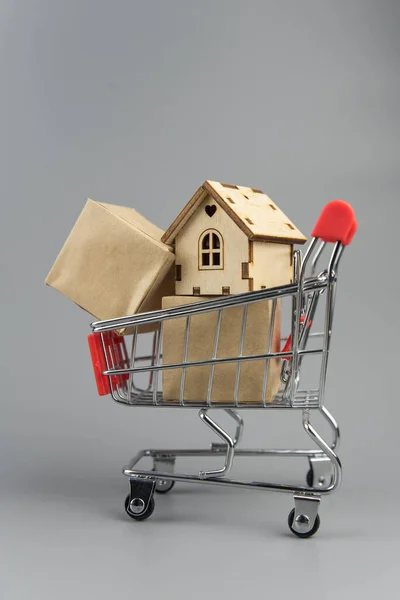 Buying a house, building repair and mortgage concept. Estimation real estate property with loan money and banking. House in shopping cart on grey background.