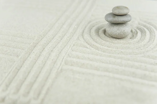 Zen bahçesi. Beyaz ve gri Zen taşlarından piramitler soyut dalga çizimleriyle beyaz kumun üzerinde. Uyum kavramı, denge ve meditasyon, spa, masaj, rahatlama.