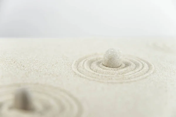 Zen garden. Pyramids of white and gray zen stones on the white sand with abstract wave drawings. Concept of harmony, balance and meditation, spa, massage, relax.