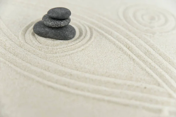 Zen bahçesi. Beyaz ve gri Zen taşlarından piramitler soyut dalga çizimleriyle beyaz kumun üzerinde. Uyum kavramı, denge ve meditasyon, spa, masaj, rahatlama.