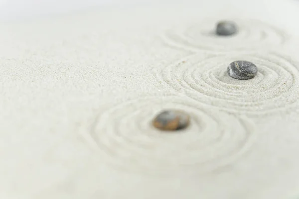 Zen bahçesi. Beyaz ve gri Zen taşlarından piramitler soyut dalga çizimleriyle beyaz kumun üzerinde. Uyum kavramı, denge ve meditasyon, spa, masaj, rahatlama.