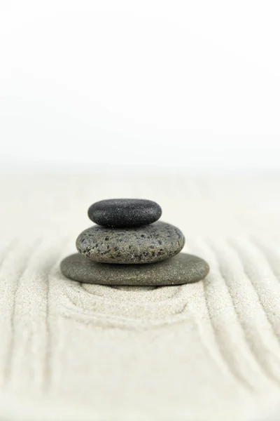 Zen bahçesi. Beyaz ve gri Zen taşlarından piramitler soyut dalga çizimleriyle beyaz kumun üzerinde. Uyum kavramı, denge ve meditasyon, spa, masaj, rahatlama.