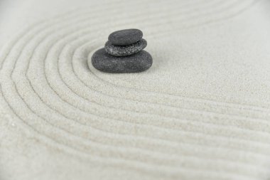Zen bahçesi. Beyaz ve gri Zen taşlarından piramitler soyut dalga çizimleriyle beyaz kumun üzerinde. Uyum kavramı, denge ve meditasyon, spa, masaj, rahatlama.
