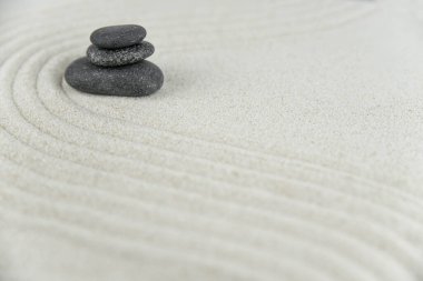 Zen bahçesi. Beyaz ve gri Zen taşlarından piramitler soyut dalga çizimleriyle beyaz kumun üzerinde. Uyum kavramı, denge ve meditasyon, spa, masaj, rahatlama.