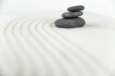 Zen bahçesi. Beyaz ve gri Zen taşlarından piramitler soyut dalga çizimleriyle beyaz kumun üzerinde. Uyum kavramı, denge ve meditasyon, spa, masaj, rahatlama.