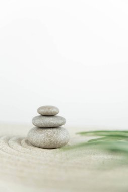 Zen bahçesi. Beyaz ve gri Zen taşlarından piramitler soyut dalga çizimleriyle beyaz kumun üzerinde. Uyum kavramı, denge ve meditasyon, spa, masaj, rahatlama.