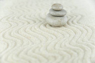 Zen bahçesi. Beyaz ve gri Zen taşlarından piramitler soyut dalga çizimleriyle beyaz kumun üzerinde. Uyum kavramı, denge ve meditasyon, spa, masaj, rahatlama.