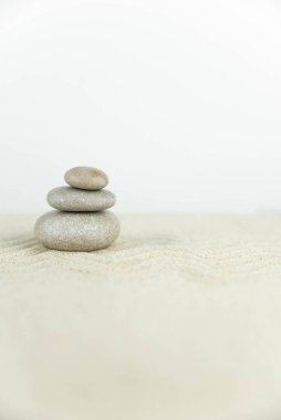 Zen bahçesi. Beyaz ve gri Zen taşlarından piramitler soyut dalga çizimleriyle beyaz kumun üzerinde. Uyum kavramı, denge ve meditasyon, spa, masaj, rahatlama.