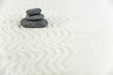 Zen bahçesi. Beyaz ve gri Zen taşlarından piramitler soyut dalga çizimleriyle beyaz kumun üzerinde. Uyum kavramı, denge ve meditasyon, spa, masaj, rahatlama.