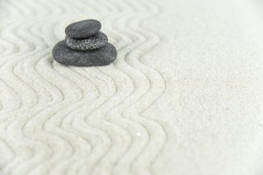 Zen bahçesi. Beyaz ve gri Zen taşlarından piramitler soyut dalga çizimleriyle beyaz kumun üzerinde. Uyum kavramı, denge ve meditasyon, spa, masaj, rahatlama.