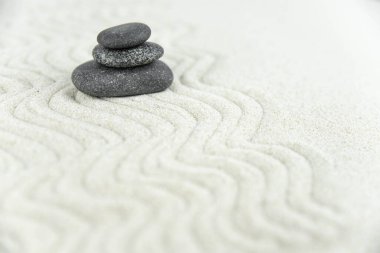 Zen bahçesi. Beyaz ve gri Zen taşlarından piramitler soyut dalga çizimleriyle beyaz kumun üzerinde. Uyum kavramı, denge ve meditasyon, spa, masaj, rahatlama.