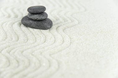 Zen bahçesi. Beyaz ve gri Zen taşlarından piramitler soyut dalga çizimleriyle beyaz kumun üzerinde. Uyum kavramı, denge ve meditasyon, spa, masaj, rahatlama.
