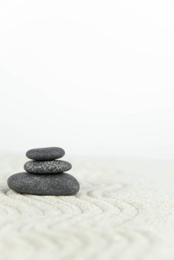 Zen bahçesi. Beyaz ve gri Zen taşlarından piramitler soyut dalga çizimleriyle beyaz kumun üzerinde. Uyum kavramı, denge ve meditasyon, spa, masaj, rahatlama.