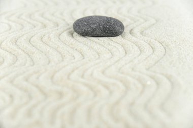 Zen bahçesi. Beyaz ve gri Zen taşlarından piramitler soyut dalga çizimleriyle beyaz kumun üzerinde. Uyum kavramı, denge ve meditasyon, spa, masaj, rahatlama.