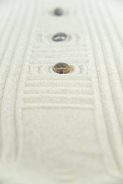 Zen bahçesi. Beyaz ve gri Zen taşlarından piramitler soyut dalga çizimleriyle beyaz kumun üzerinde. Uyum kavramı, denge ve meditasyon, spa, masaj, rahatlama.