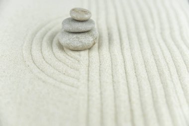 Zen bahçesi. Beyaz ve gri Zen taşlarından piramitler soyut dalga çizimleriyle beyaz kumun üzerinde. Uyum kavramı, denge ve meditasyon, spa, masaj, rahatlama.